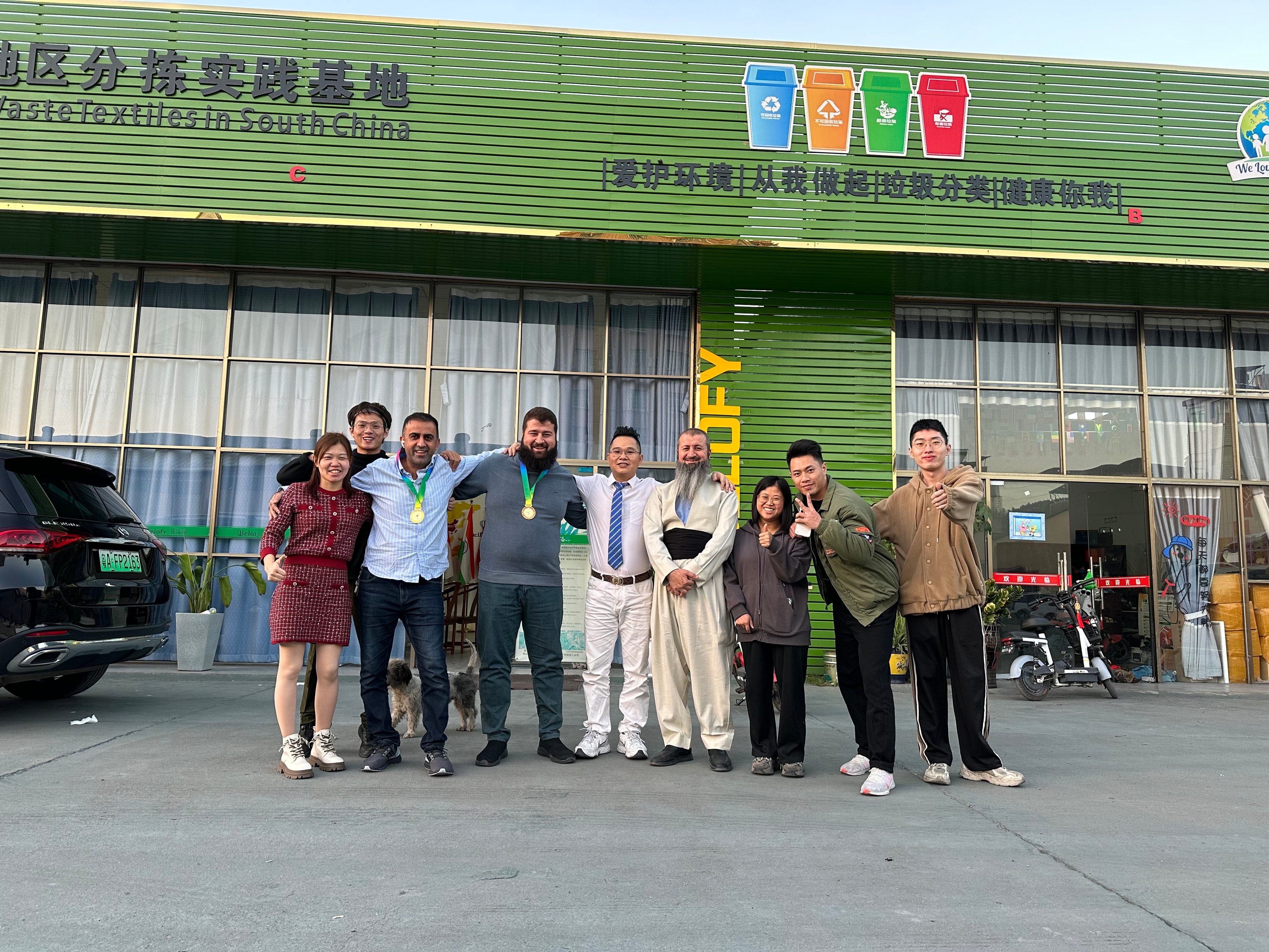 Group posing outside green recycling facility Belofy